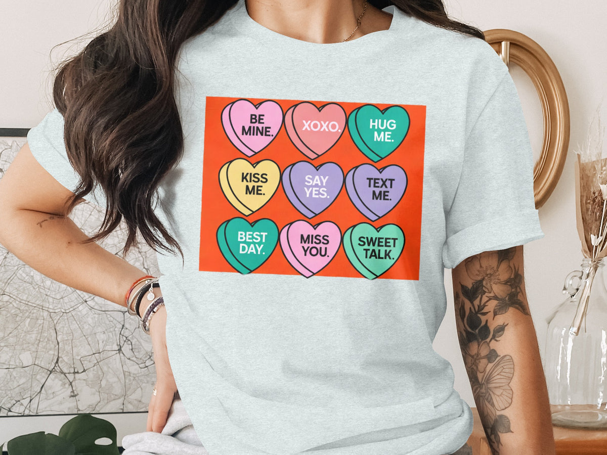 Light blue t-shirt with candy heart graphic: "Be Mine," "XOXO," "Hug Me," "Kiss Me," "Say Yes," "Text Me," "Best Day," "Miss You," "Sweet Talk."