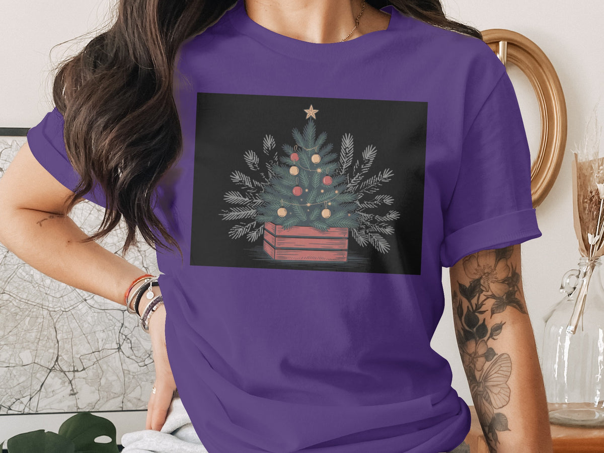 Purple t-shirt featuring a decorated Christmas tree in a wooden crate.