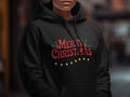 A person wears a black hoodie printed with red Merry Christmas text and string lights.