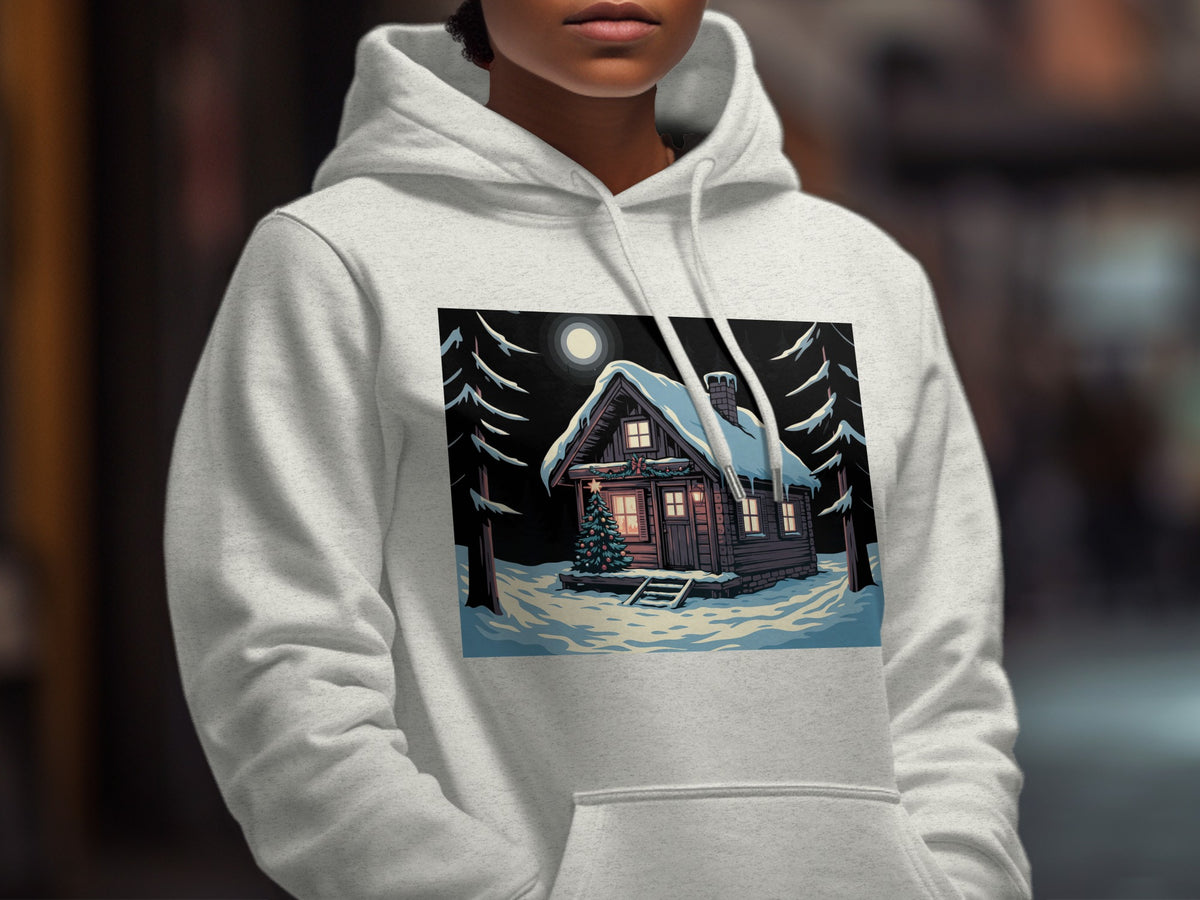 A person wearing a light gray hooded sweatshirt with a winter cabin graphic on the chest.