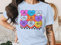 Light blue t-shirt with a graphic of conversation hearts featuring text like "BE MINE", "XOXO", and "LOVE".