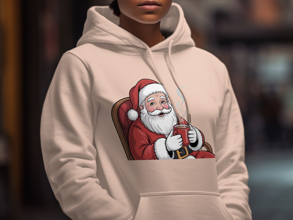 A person wears a light pink hoodie featuring a graphic of Santa Claus drinking hot cocoa.