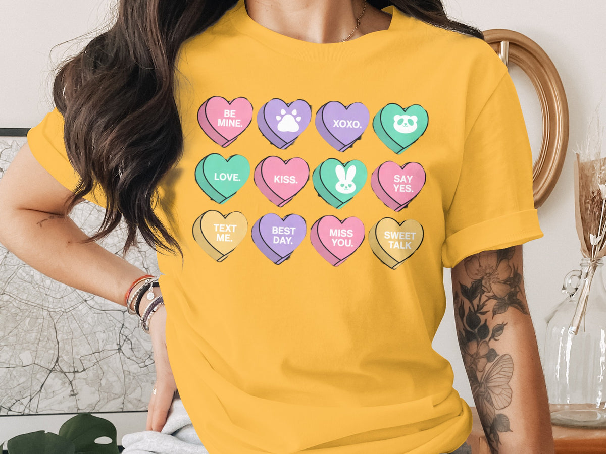 Yellow t-shirt with rows of conversation heart candies featuring text and icons.