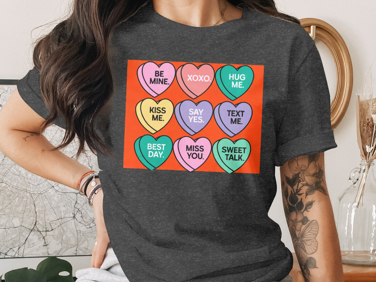 Dark grey t-shirt with conversation heart graphics saying "Be Mine," "XOXO," "Hug Me," etc.