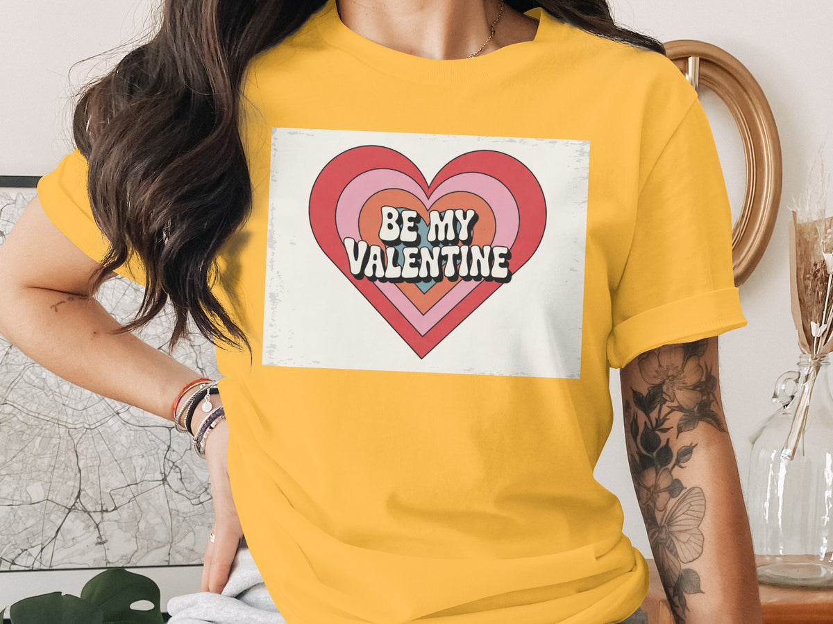 Yellow t-shirt with a heart graphic that reads "BE MY VALENTINE".