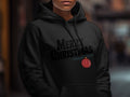 A person wearing a black hoodie with the text Merry Christmas and a red ornament graphic.