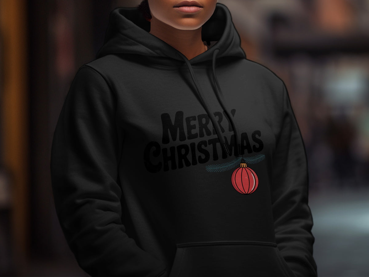 A person wearing a black hoodie with the text Merry Christmas and a red ornament graphic.