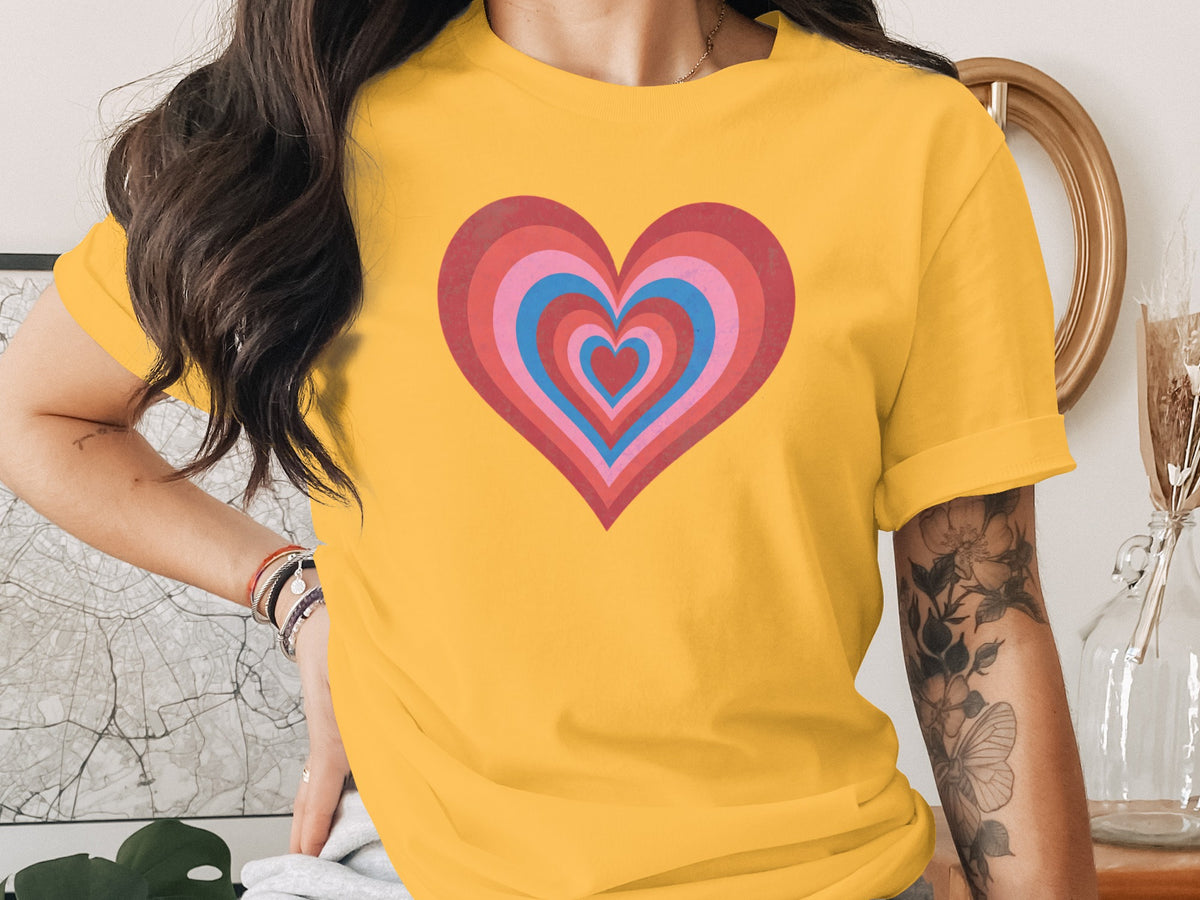 A person wearing a bright yellow t-shirt featuring a large, colorful nested heart graphic on the chest.