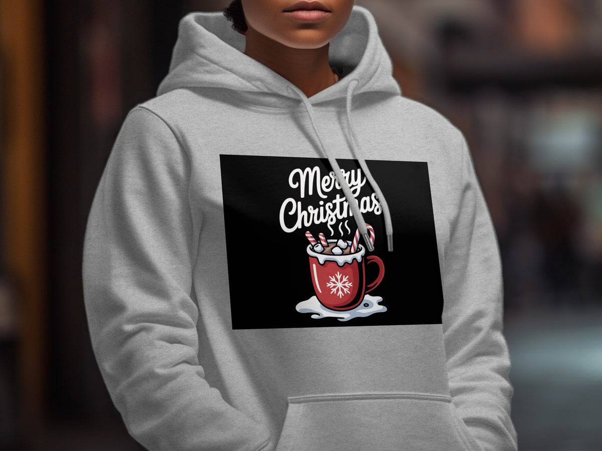 A person wearing a light gray hoodie printed with a Merry Christmas graphic featuring a red cocoa mug.