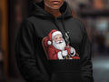 Santa Claus in armchair holding mug of hot beverage on black hoodie design.