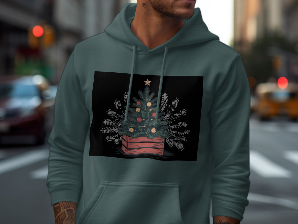 Dark green hoodie with a black rectangle featuring a decorated Christmas tree in a wooden crate.