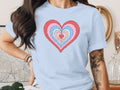 Light blue t-shirt with a colorful concentric heart graphic and rolled-up sleeves.