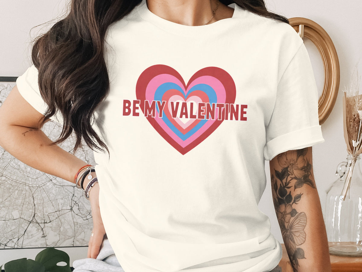 Cream t-shirt with layered heart graphic and "BE MY VALENTINE" text.