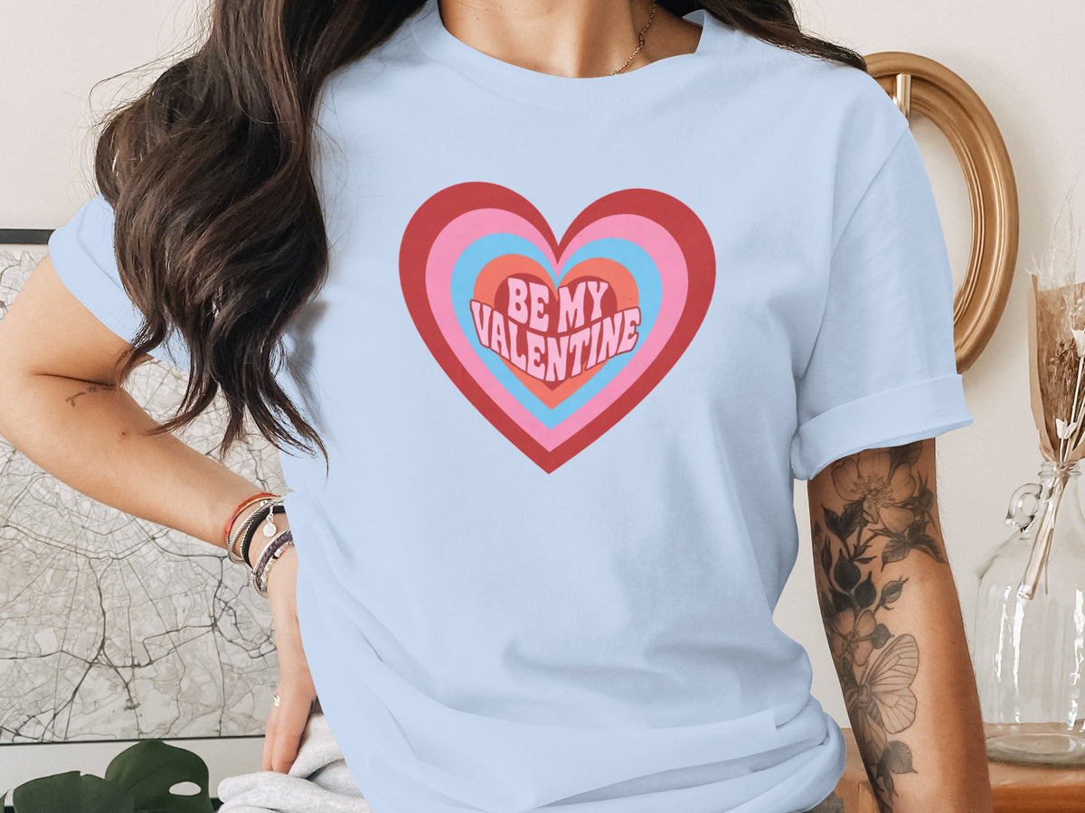 Light blue t-shirt with concentric hearts graphic and "BE MY VALENTINE" text.