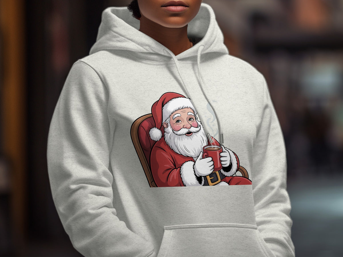 Santa Claus in a red suit holding a red mug on a light grey hoodie.