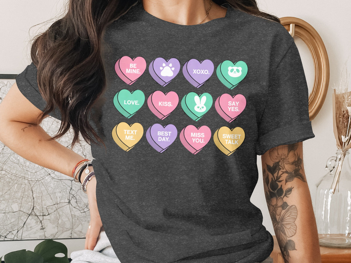 A dark gray t-shirt featuring twelve colorful conversation hearts printed on the chest with romantic messages and icons.