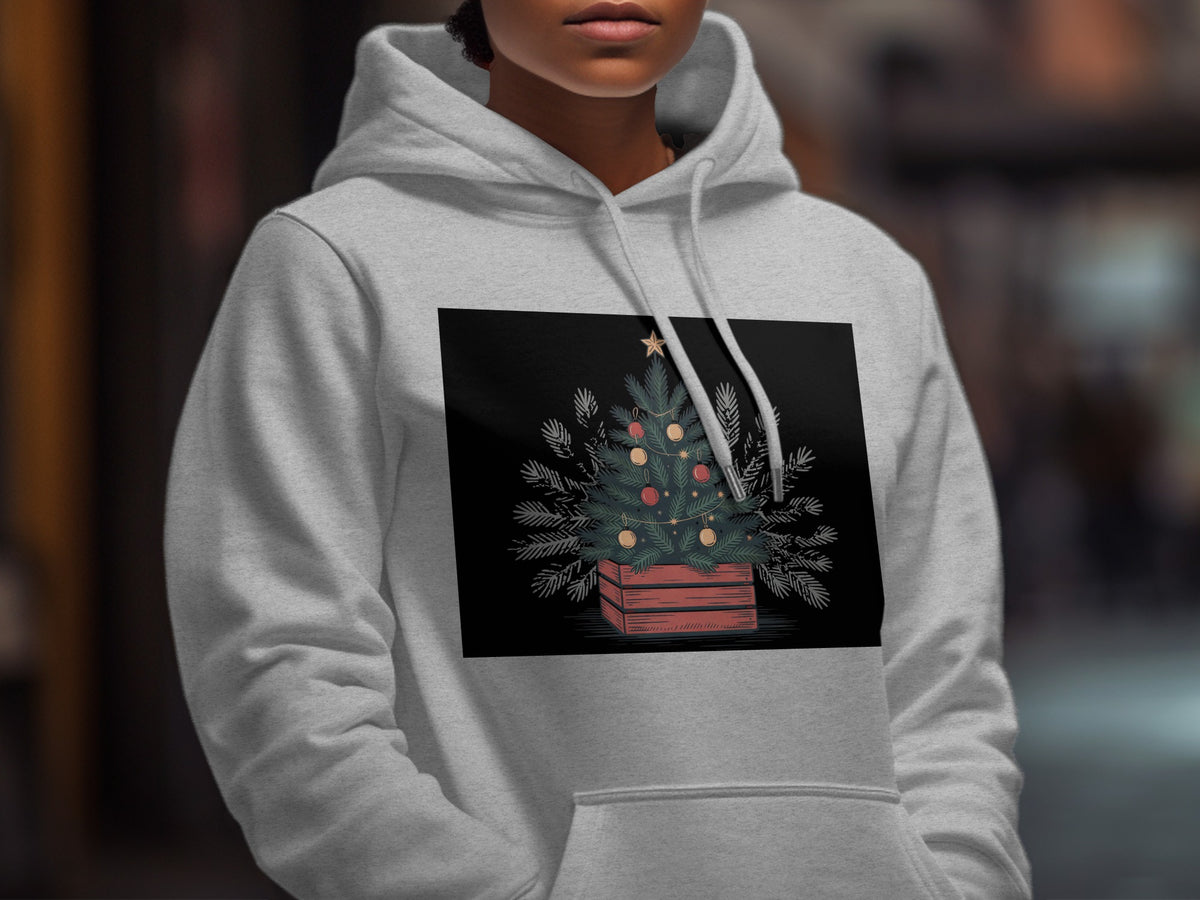 A person wearing a grey hoodie featuring a graphic of a decorated Christmas tree in a crate.