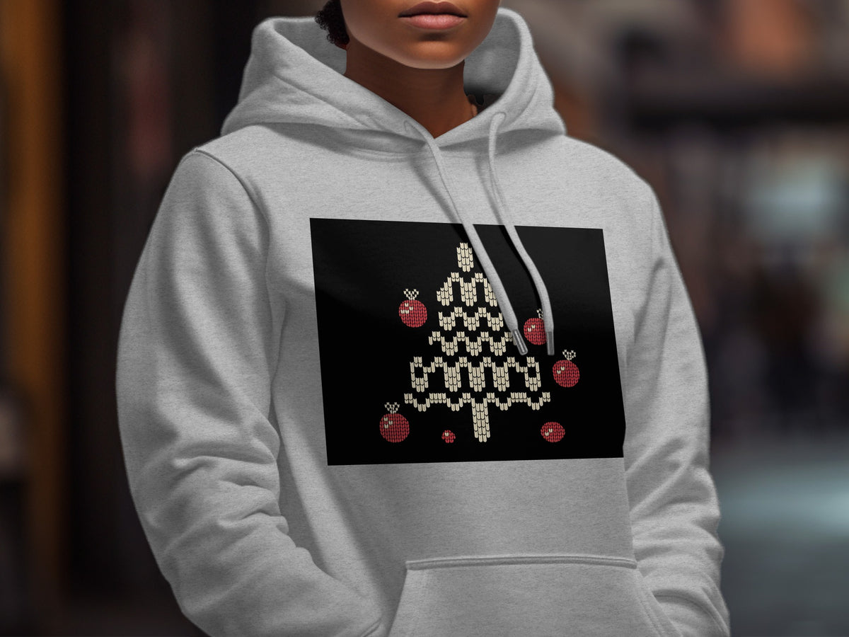 A person wears a light gray hoodie featuring a black rectangular graphic of a white Christmas tree with red ornaments.