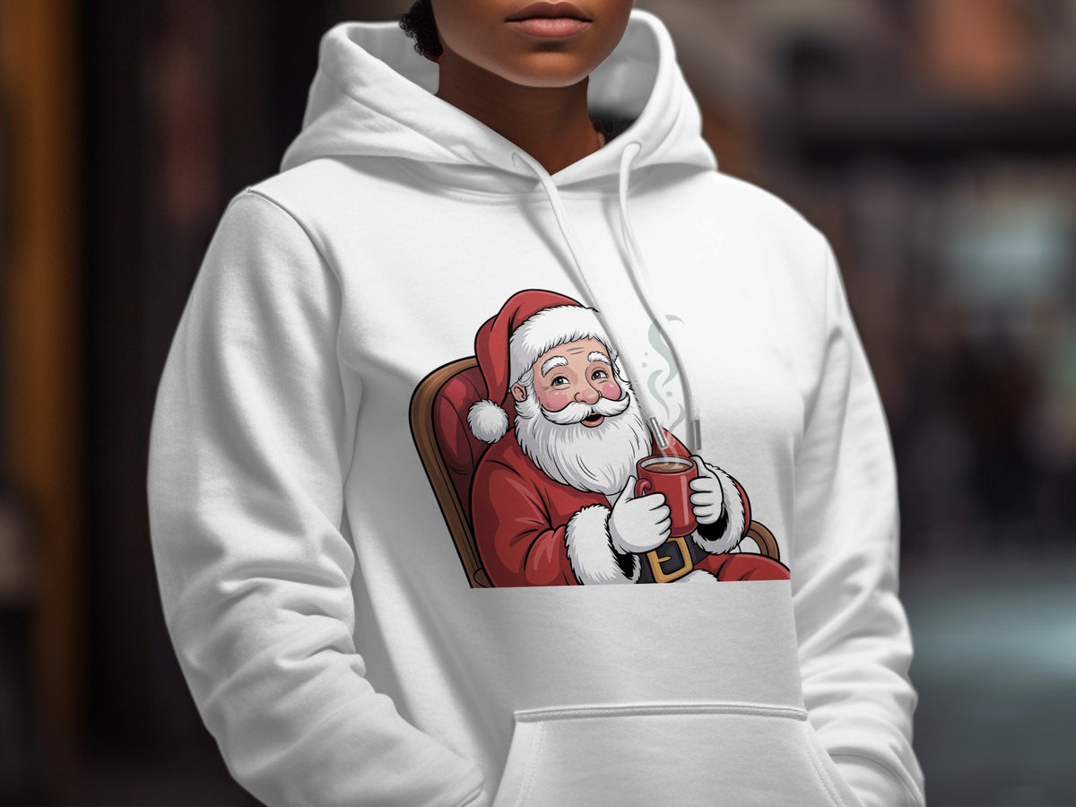 A person wearing a white hooded sweatshirt printed with a cartoon graphic of Santa Claus drinking from a red mug.