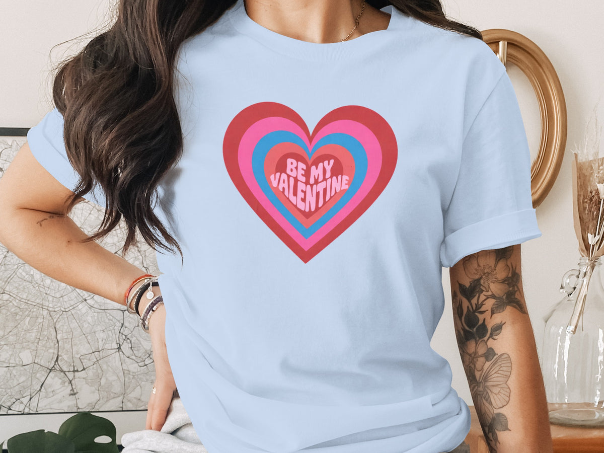 Light blue t-shirt with concentric hearts graphic and "BE MY VALENTINE" text.