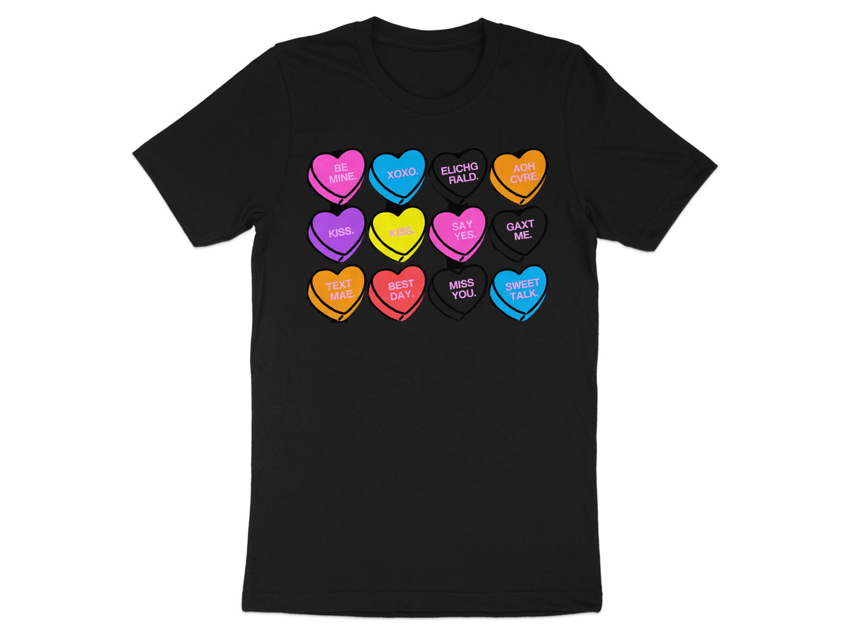 A black t-shirt printed with a grid of twelve colorful Valentine candy hearts containing messages.