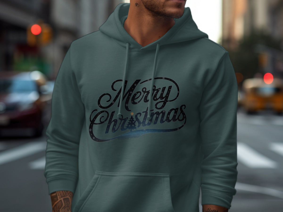A man wears a dark teal hoodie featuring a black Merry Christmas graphic with a small tree.