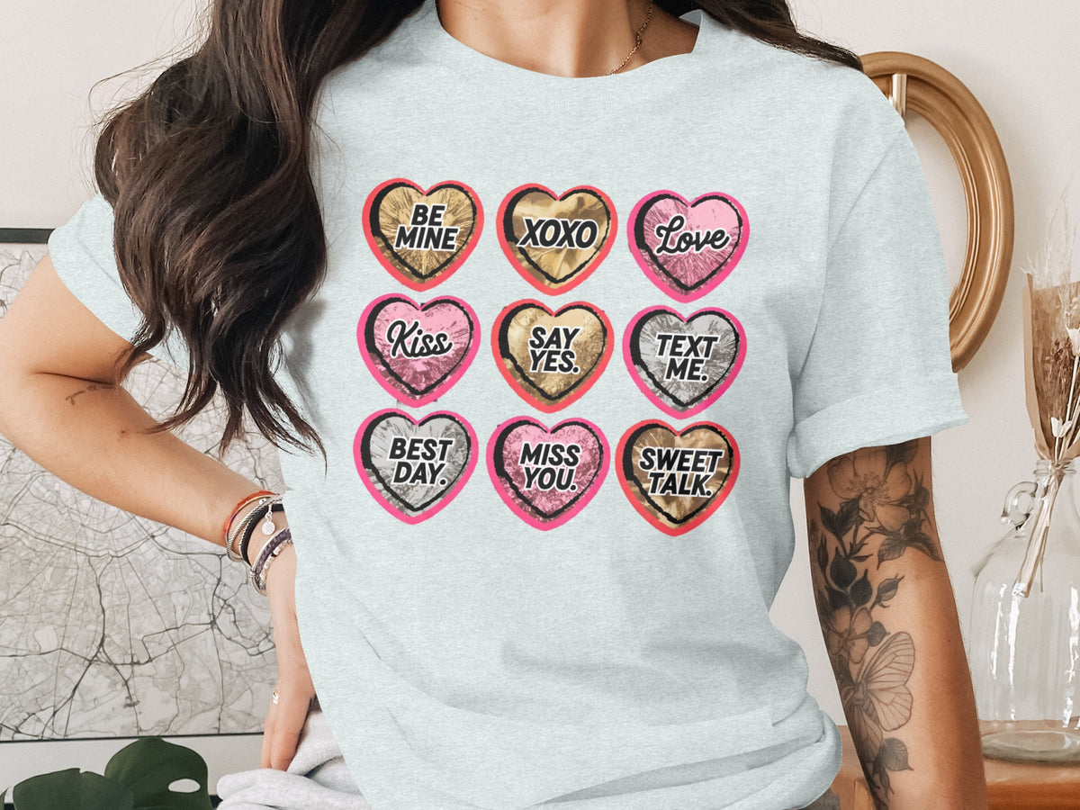 Light blue t-shirt with nine candy hearts with text: Be Mine, XOXO, Love, Kiss, Say Yes, Text Me, Best Day, Miss You, Sweet Talk.