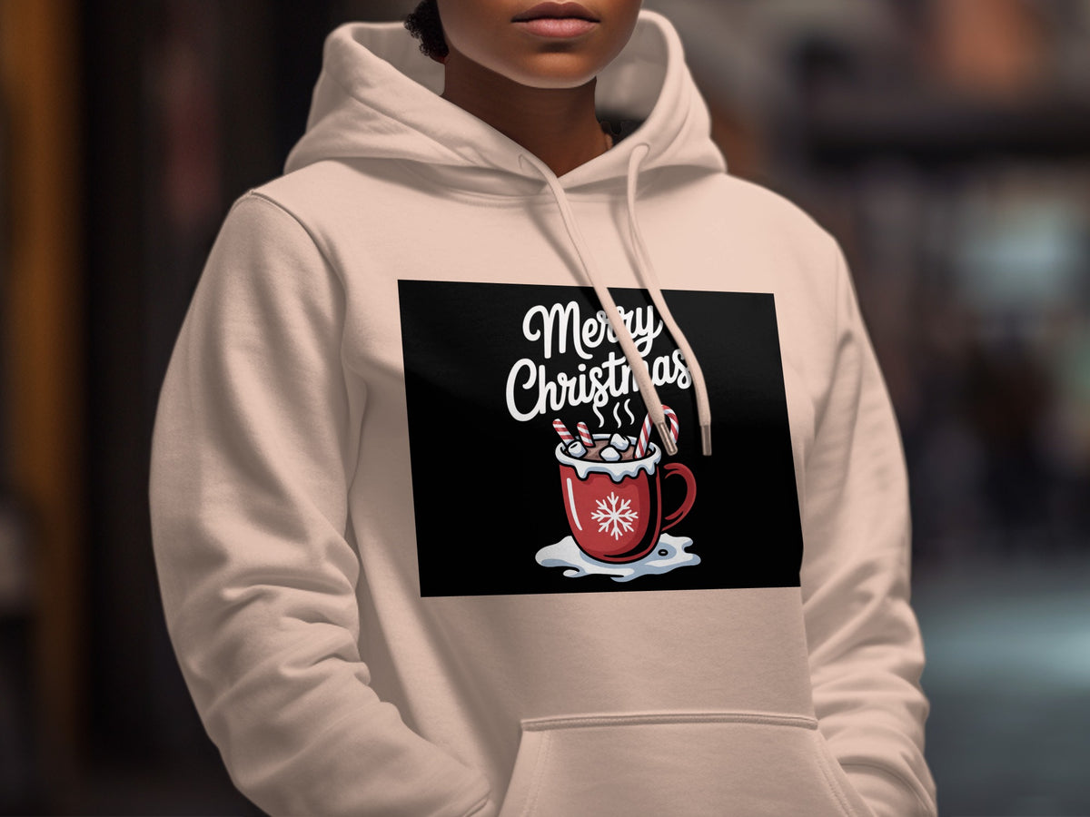 A person wearing a cream-colored hoodie featuring a graphic of a red mug with hot cocoa, candy canes, and the text Merry Christmas.