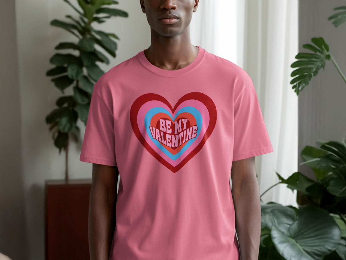 Man wearing pink t-shirt with "Be My Valentine" graphic in a multi-colored heart.
