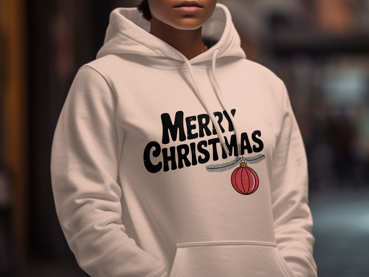A person wearing a white hooded sweatshirt with Merry Christmas text and an ornament graphic.