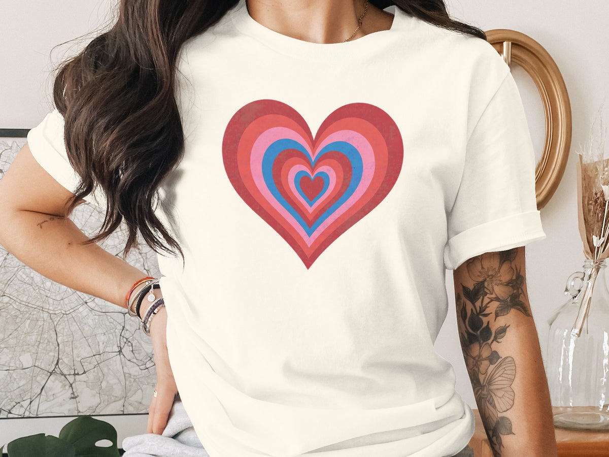 Cream t-shirt with concentric heart graphic in shades of pink, red, and blue.