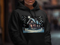 A black hoodie featuring a graphic print of a snowy cabin under a full moon.